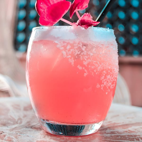 Pink La Mesa Modern Mexican cocktail with a salted rim and pink flower garnish.
