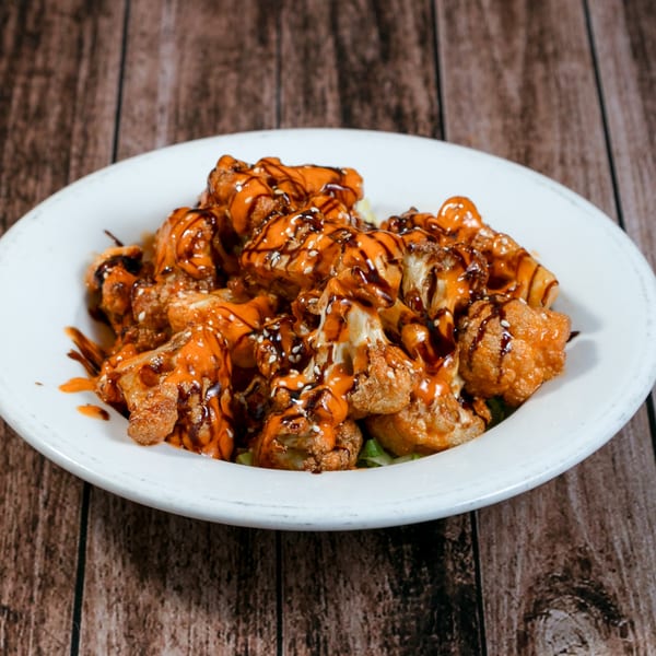 La Mesa's crispy cauliflower bites, drizzled with orange and dark sauces, topped with sesame seeds.