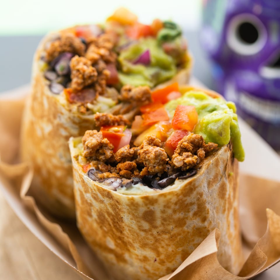 Two La Mesa Modern Mexican burritos, filled with meat, guacamole, tomatoes, and black beans.