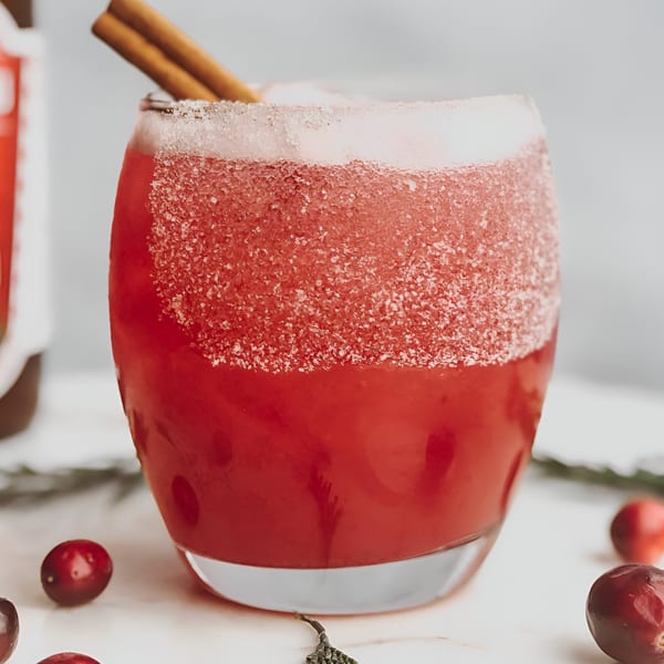 A vibrant red La Mesa Modern Mexican cocktail with a sugared rim and cinnamon stick garnish.