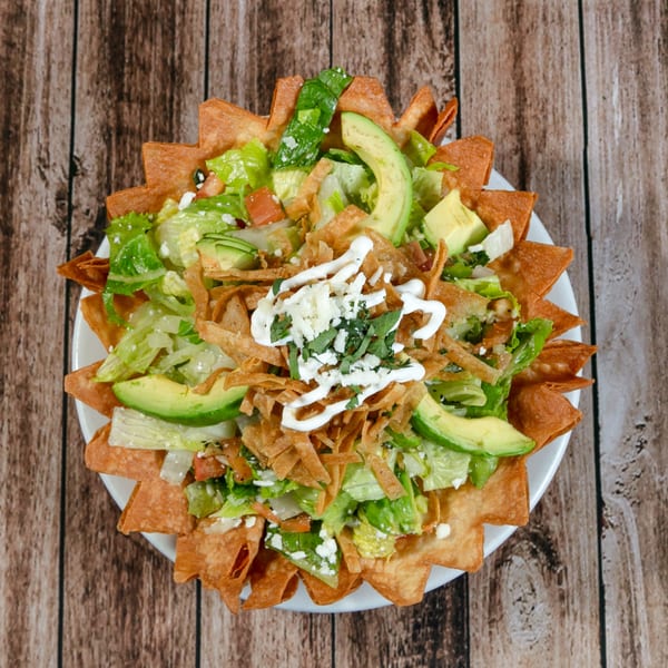 La Mesa Modern Mexican taco salad with lettuce, avocado, cheese, and sour cream in a tortilla bowl.